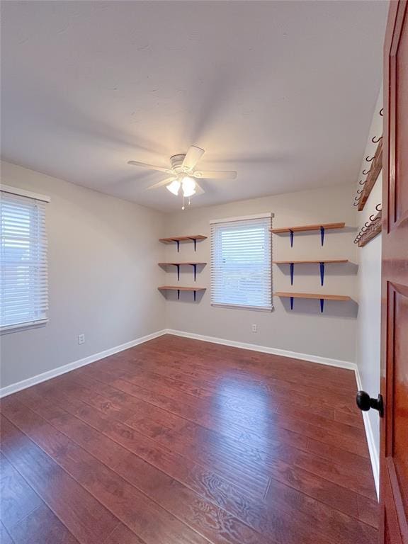 empty room featuring baseboards, dark wood finished floors, and a ceiling fan