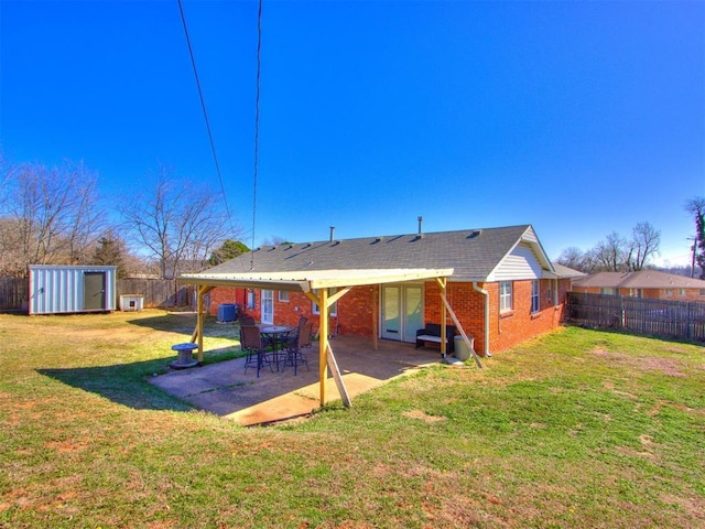 rear view of house with an outbuilding, a shed, a fenced backyard, a lawn, and brick siding