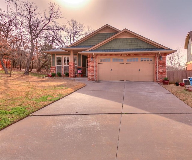 craftsman-style home with a garage, brick siding, concrete driveway, and a yard