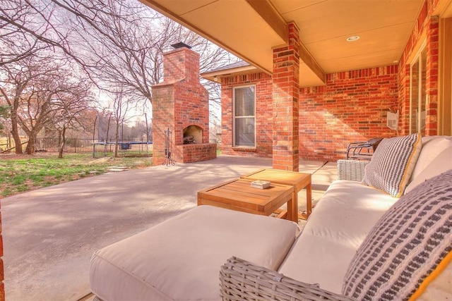 view of patio featuring an outdoor living space with a fireplace, a trampoline, and fence