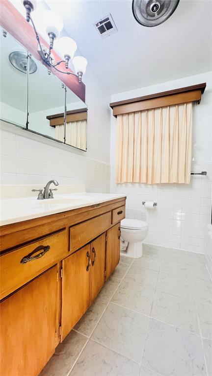 3731 Newport St, Oklahoma City, OK 73112 - bathroom with tile walls, visible vents, toilet, and vanity