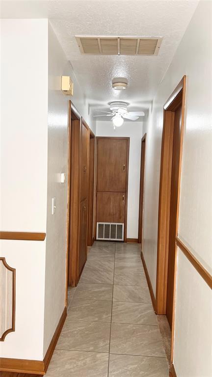 3731 Newport St, Oklahoma City, OK 73112 - hallway with baseboards, a textured ceiling, and visible vents
