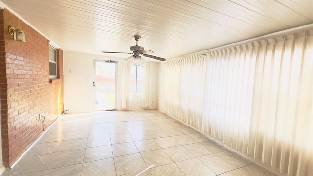 3731 Newport St, Oklahoma City, OK 73112 - empty room with a ceiling fan, light tile patterned floors, and brick wall