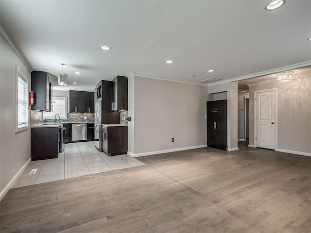 kitchen featuring light wood finished floors, open floor plan, dishwasher, light countertops, and decorative backsplash