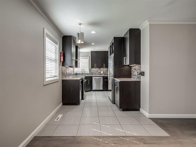 kitchen featuring backsplash, appliances with stainless steel finishes, light countertops, and baseboards