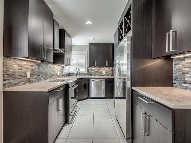 kitchen featuring wall chimney range hood, backsplash, appliances with stainless steel finishes, and a sink