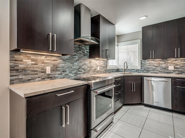 kitchen featuring a sink, light countertops, appliances with stainless steel finishes, wall chimney range hood, and tasteful backsplash