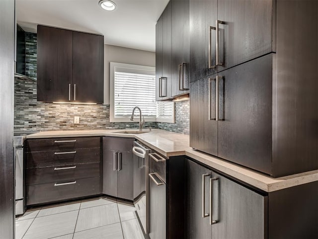 kitchen featuring a sink, tasteful backsplash, stainless steel dishwasher, light countertops, and dark brown cabinets