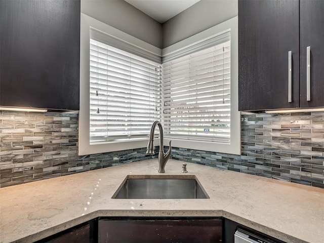 kitchen with dishwasher, light stone countertops, backsplash, and a sink