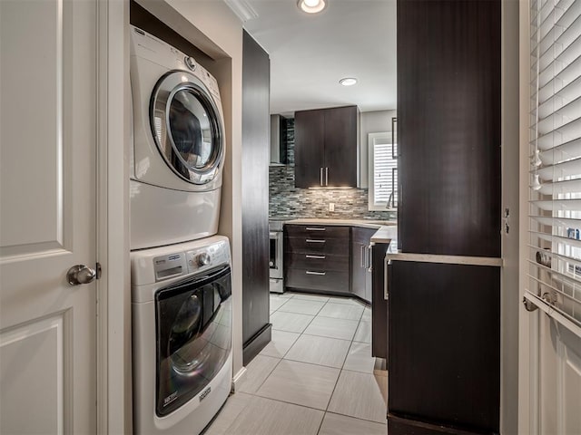 washroom with recessed lighting, stacked washer and clothes dryer, light tile patterned flooring, and laundry area