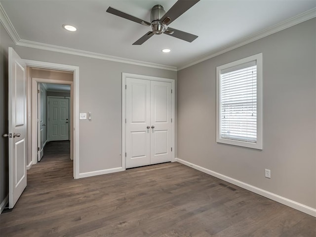 unfurnished bedroom with a closet, baseboards, ornamental molding, and dark wood finished floors