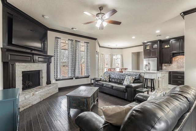 2241 W Mickey Dr, Mustang, OK 73064 - living area featuring visible vents, a ceiling fan, crown molding, a fireplace, and dark wood-type flooring