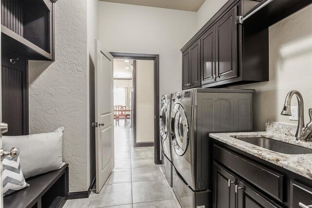 2241 W Mickey Dr, Mustang, OK 73064 - clothes washing area featuring washing machine and clothes dryer, a sink, light tile patterned flooring, a textured wall, and cabinet space