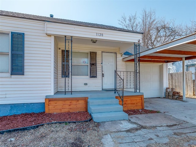 view of exterior entry featuring concrete driveway, an attached garage, a carport, and covered porch