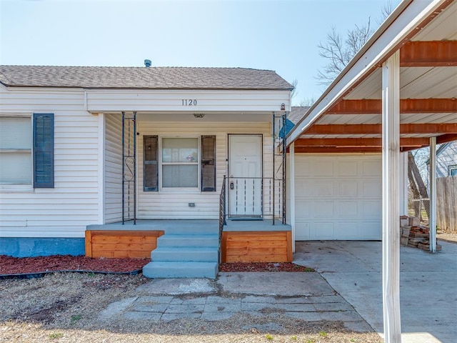 view of front of house featuring a porch, roof with shingles, a garage, a carport, and driveway