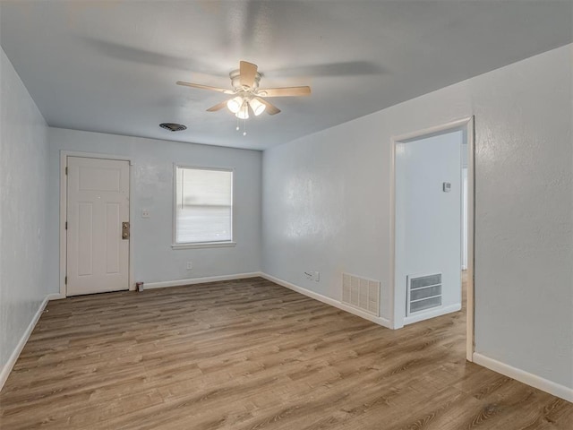 spare room featuring a ceiling fan, wood finished floors, visible vents, and baseboards