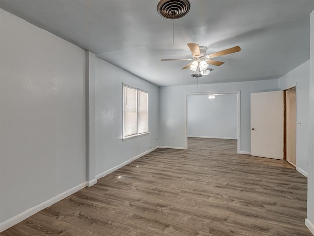 empty room with visible vents, baseboards, a ceiling fan, and wood finished floors