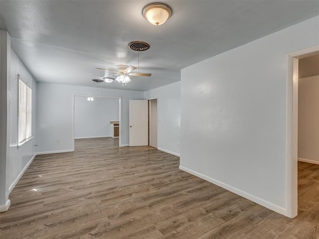 empty room featuring visible vents, baseboards, ceiling fan, and wood finished floors