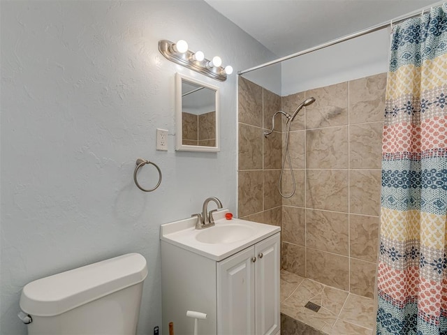 full bathroom with tiled shower, toilet, vanity, and a textured wall