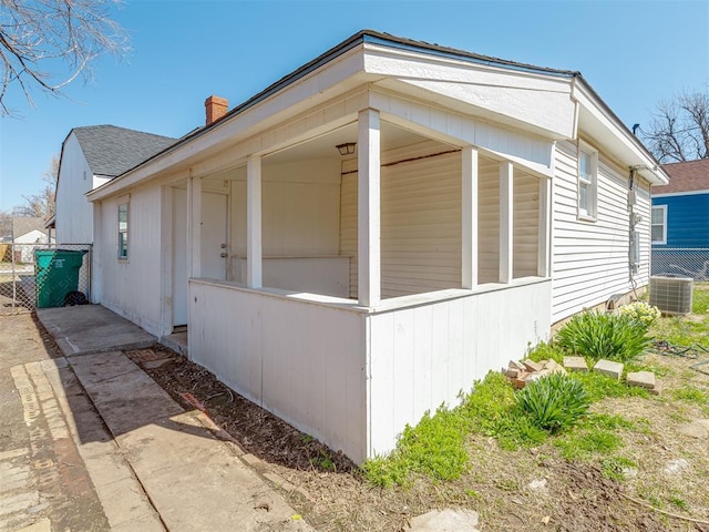 view of side of home featuring a shingled roof, central air condition unit, fence, and a chimney