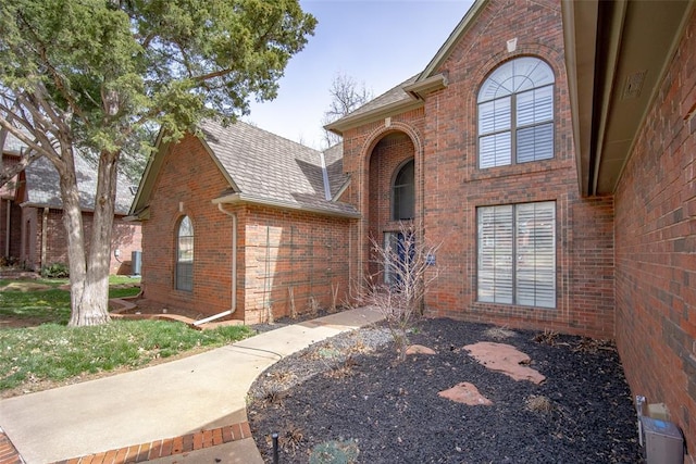 traditional home featuring brick siding and roof with shingles