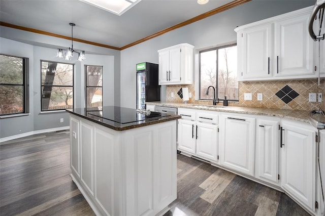 kitchen with dark wood finished floors, a sink, white cabinetry, crown molding, and a center island