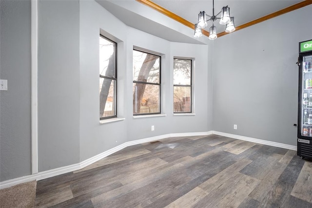 interior space with baseboards, a notable chandelier, wood finished floors, and ornamental molding