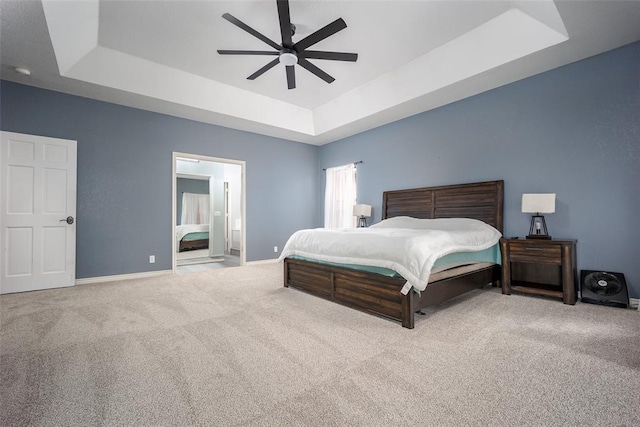 bedroom featuring a ceiling fan, baseboards, carpet floors, ensuite bathroom, and a raised ceiling