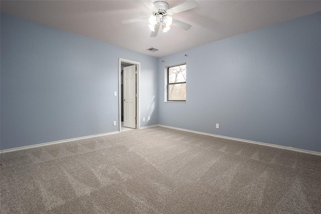 empty room with visible vents, baseboards, carpet, and a ceiling fan