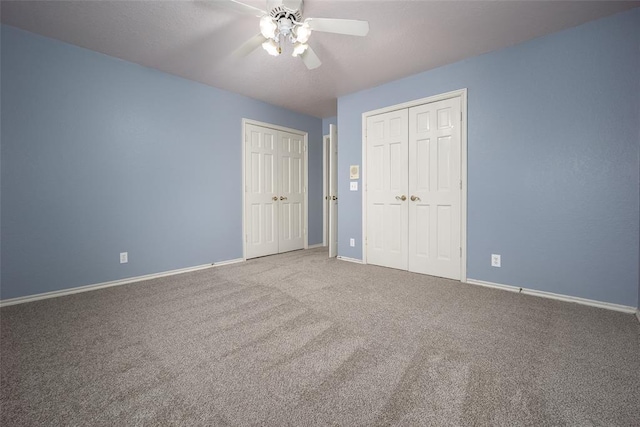 unfurnished bedroom featuring carpet flooring, ceiling fan, baseboards, and multiple closets