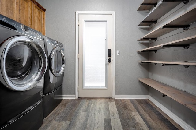 washroom featuring cabinet space, washing machine and dryer, baseboards, and dark wood-style flooring