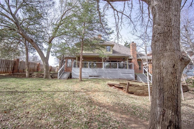 rear view of property with fence, stairs, a chimney, a yard, and a sunroom