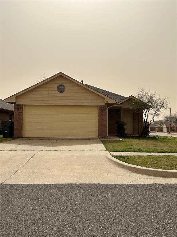 view of front of home with a front lawn, brick siding, an attached garage, and driveway