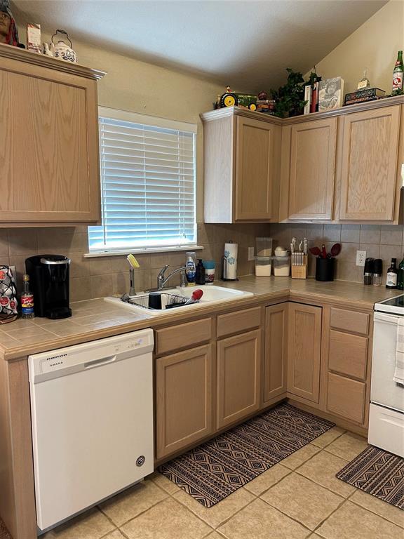 kitchen with white appliances, tile countertops, light tile patterned floors, a sink, and tasteful backsplash