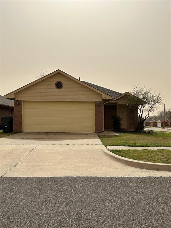 view of front of house with a front lawn, a garage, brick siding, and driveway