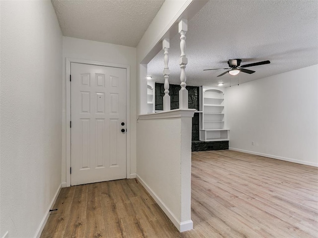 interior space with built in features, wood finished floors, baseboards, and a textured ceiling