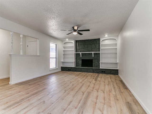 unfurnished living room featuring built in shelves, baseboards, wood finished floors, a textured ceiling, and a ceiling fan