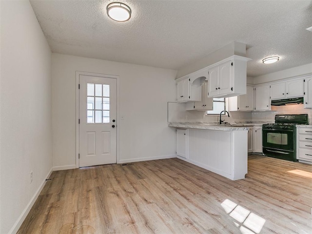 kitchen featuring white cabinetry, light countertops, plenty of natural light, and black range with gas cooktop