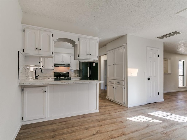 kitchen with visible vents, black appliances, a sink, ventilation hood, and a peninsula