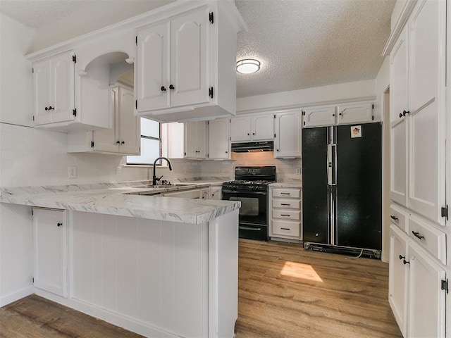 kitchen featuring black appliances, under cabinet range hood, a peninsula, wood finished floors, and white cabinetry