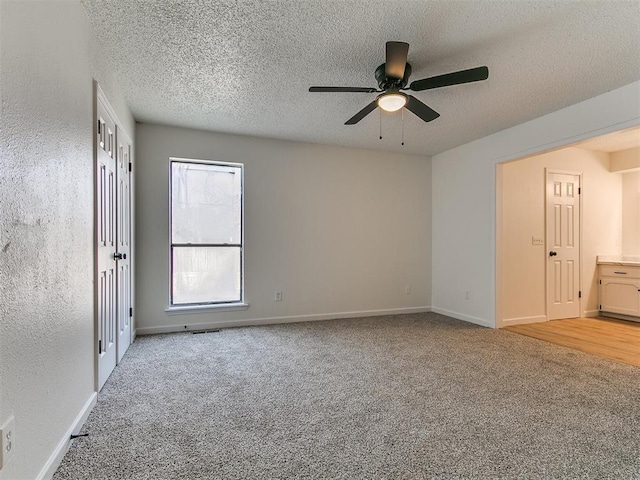 carpeted spare room with a textured ceiling, baseboards, and ceiling fan