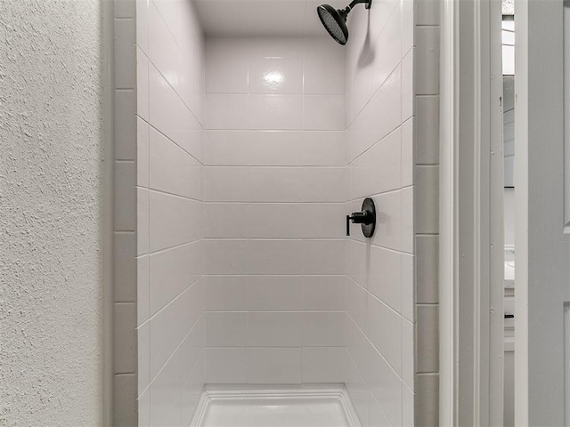 full bathroom with a textured wall and a stall shower