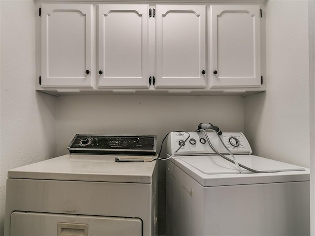 laundry room with washing machine and clothes dryer and cabinet space