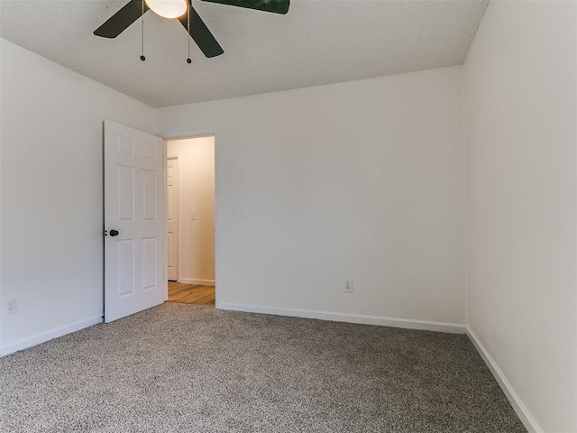 carpeted spare room featuring a textured ceiling, baseboards, and ceiling fan