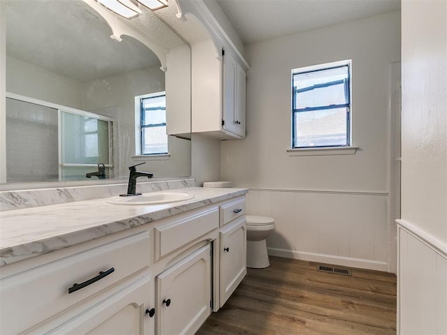 bathroom featuring visible vents, toilet, a stall shower, wood finished floors, and wainscoting