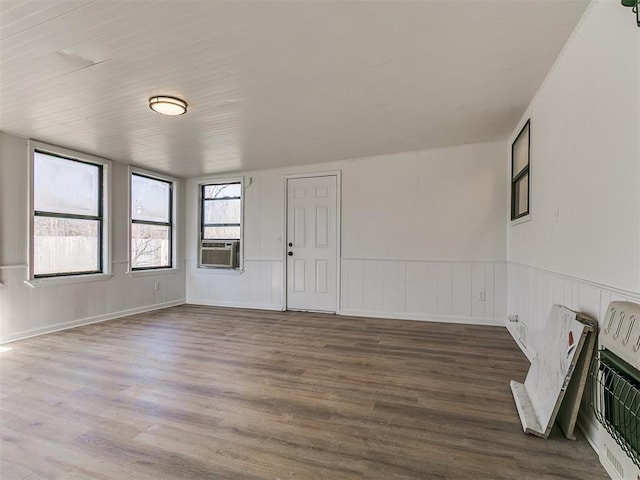 spare room with heating unit, wood finished floors, a wainscoted wall, and cooling unit