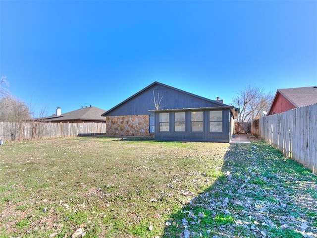 rear view of house with a lawn and a fenced backyard