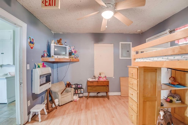 501 SE 15th St, Oklahoma City, OK 73129 - bedroom with electric panel, a textured ceiling, baseboards, heating unit, and wood finished floors