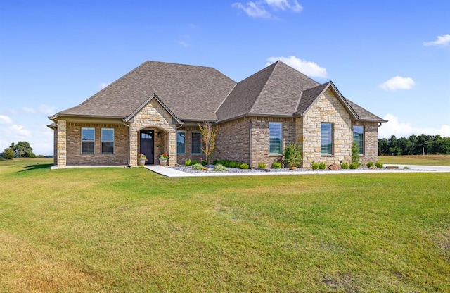 french provincial home featuring stone siding, brick siding, a front lawn, and a shingled roof