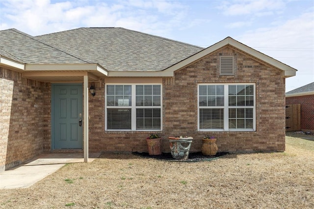 property entrance with brick siding and a shingled roof